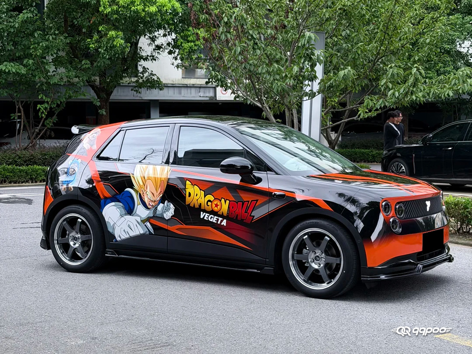 Front three-quarter view of a black car with a Dragon Ball Z Vegeta car wrap and orange-red graphics.
