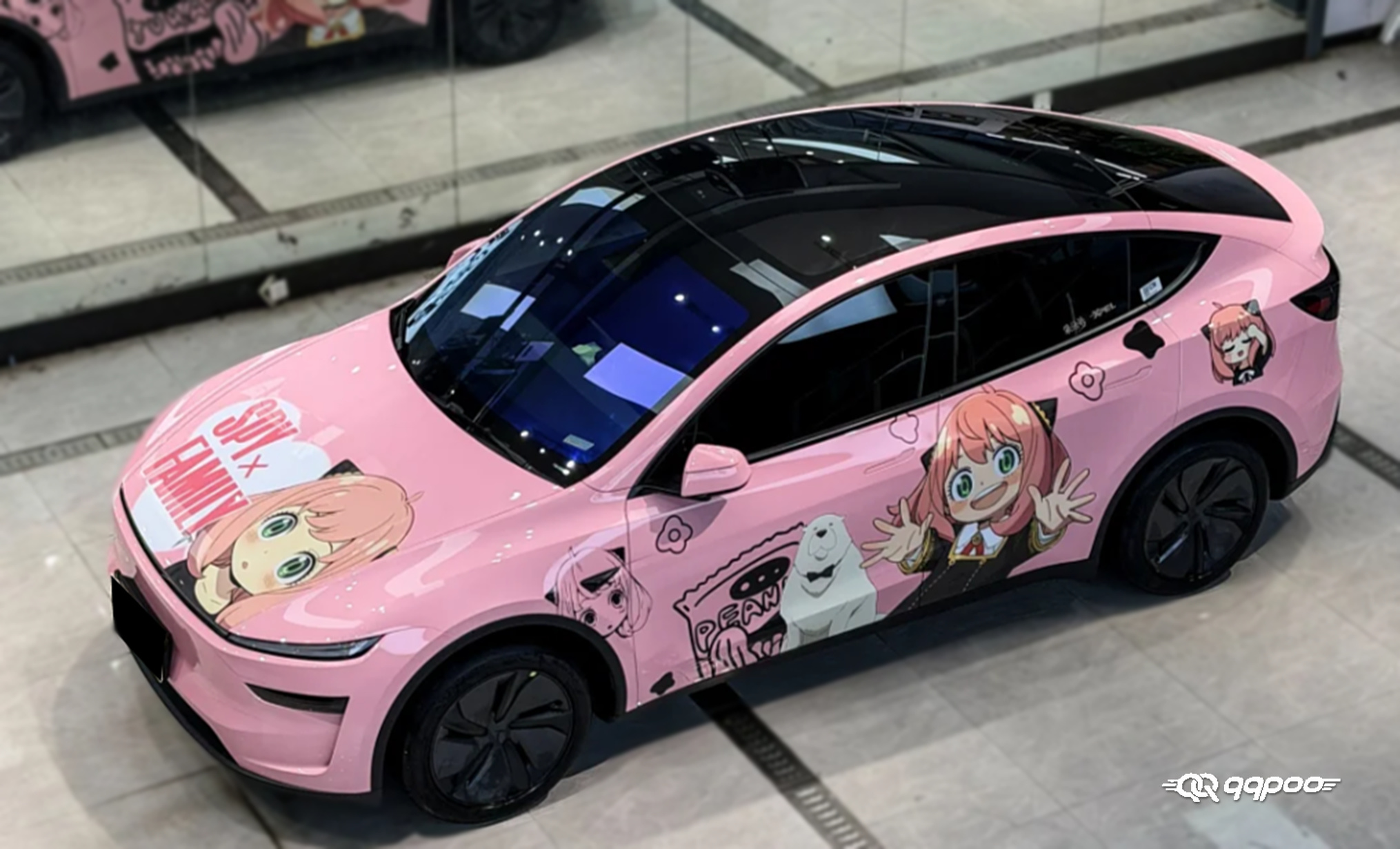 Elevated front three-quarter view of a pink car with SPY x FAMILY Anya and Bond artwork on the hood and side panels.